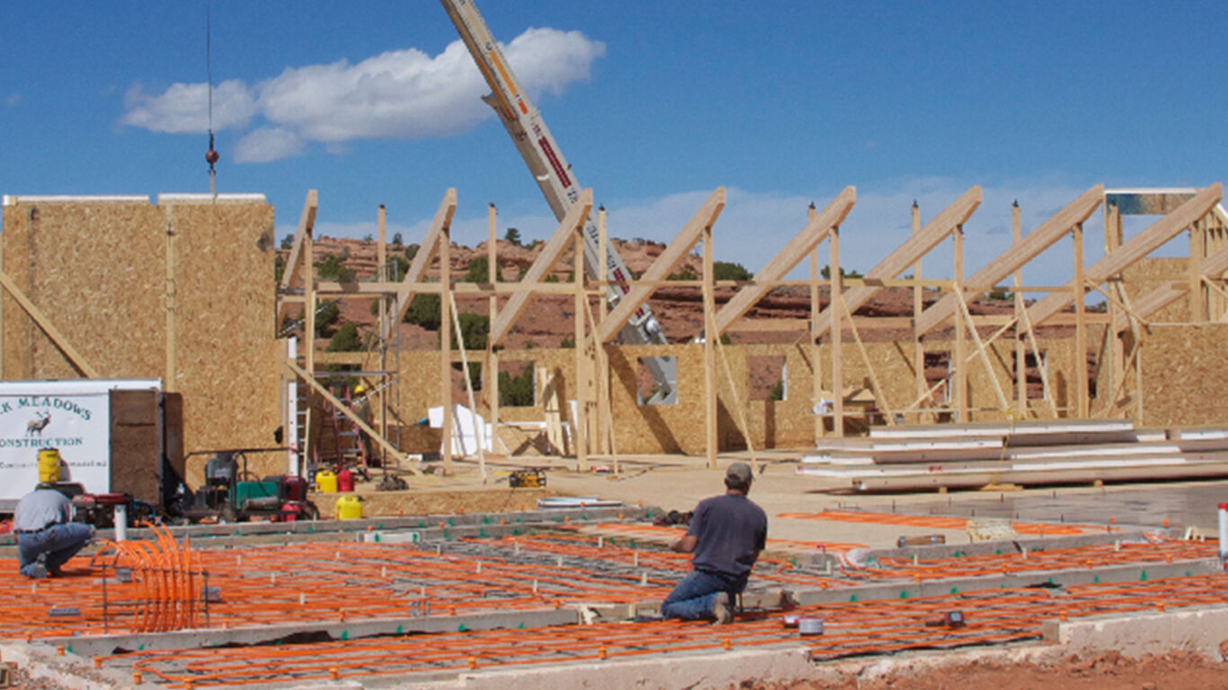 Two men at a construction site installing radiant heated flooring into the foundation.