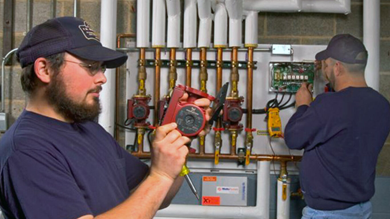 Two workers installing control pannel for floor heating system