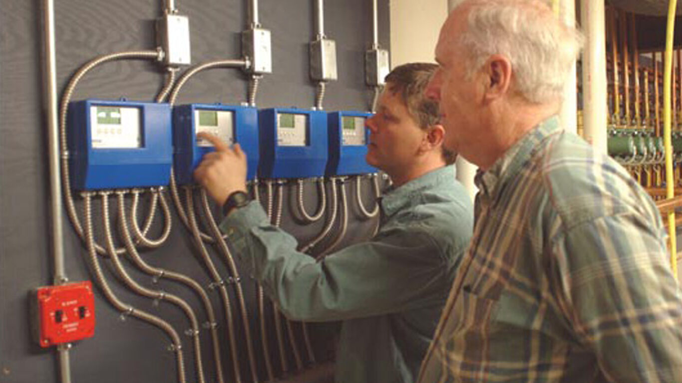 Two men looking at components to a watts system