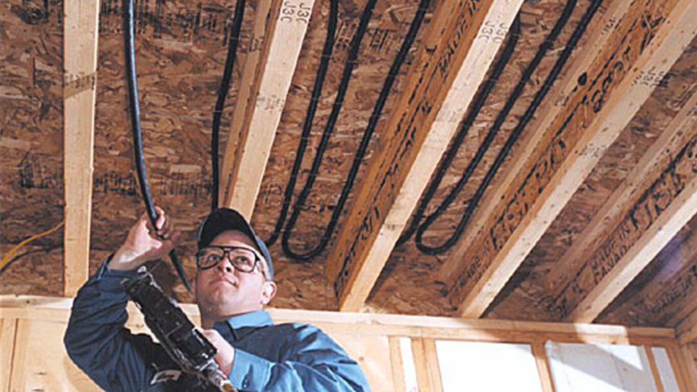 Man installing watts materials in the ceiling of the basement